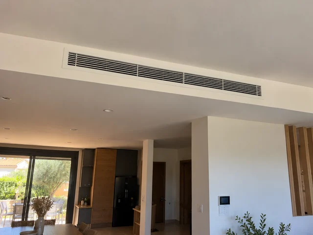 Longue grille d’aération dans le faux plafond d’un séjour-cuisine