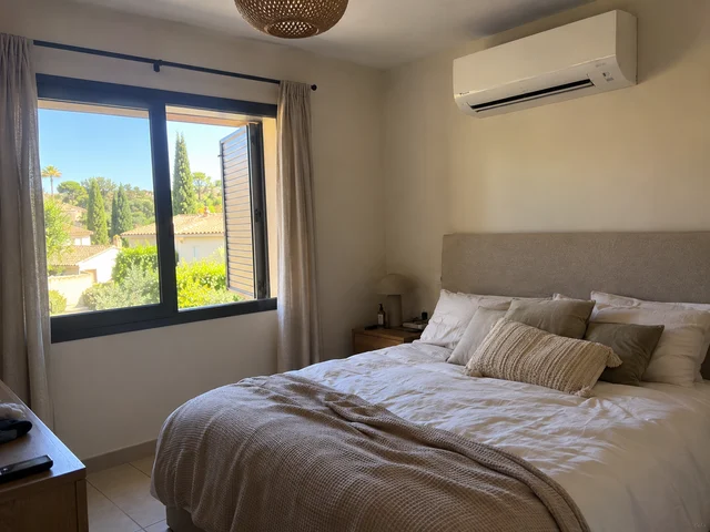 Climatiseur mural blanc au-dessus du lit dans une chambre lumineuse