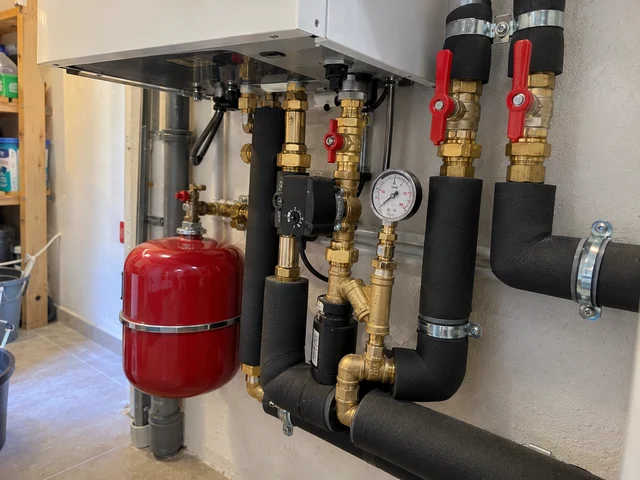 Tuyauteries isolées et vase d’expansion rouge sous un module de chauffage